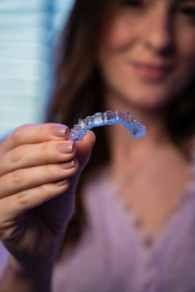 Mulher segurando alinhador invisível transparente em consultório odontológico