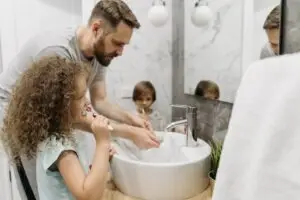 Pai e filhos escovando os dentes juntos pela manhã