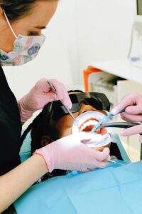 Dentista examinando gengiva de paciente durante consulta odontológica para avaliar inflamação gengival