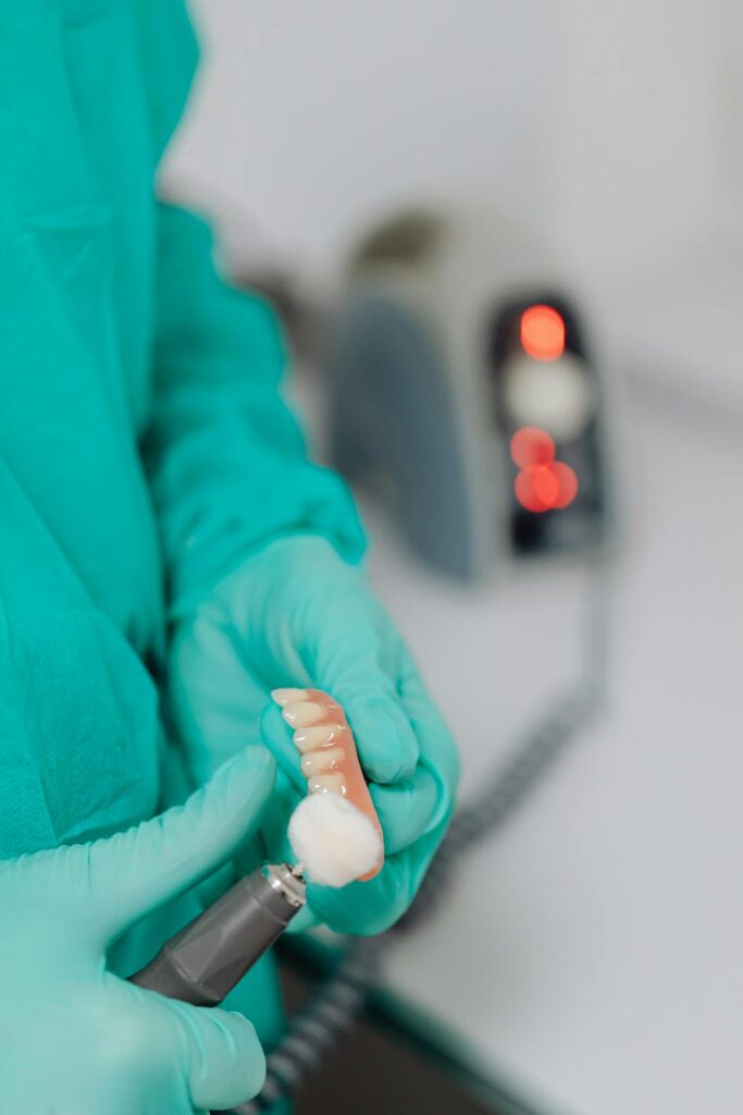 Dentista polindo prótese dentária em laboratório odontológico